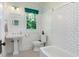 Bright bathroom featuring a pedestal sink, subway tile shower, and a window with a view of palm trees at 3000 4Th N Ave, St Petersburg, FL 33713