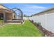 Landscaped backyard with a screened-in lanai and white privacy fence at 313 Old Windsor Way, Spring Hill, FL 34609