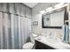A clean, bright bathroom with a shower curtain, modern vanity and framed mirror at 3829 Trophy Blvd, New Port Richey, FL 34655