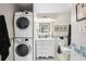 Well lit bathroom with stacked washer and dryer next to the vanity, toilet, and accent tile at 3829 Trophy Blvd, New Port Richey, FL 34655