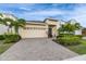 Welcoming single-Gathering home with a brick driveway, lush landscaping, and an attached two-car garage at 407 Sandsend Ct, Apollo Beach, FL 33572