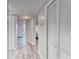 Hallway with white doors, light gray walls, and wood-style floors leads to the front door and bedroom at 4650 Bay Blvd # 1012, Port Richey, FL 34668