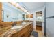 A large bathroom with a granite countertop, dual sinks, vanity lighting, and warm tones at 5900 Bahia Del Mar Cir # 137, St Petersburg, FL 33715