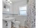 Well-lit bathroom with a pedestal sink, tiled walls, and a shower featuring a floral curtain at 6618 3Rd N Ave, St Petersburg, FL 33710