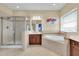 Bright bathroom featuring a soaking tub, glass shower, and tiled floor at 7100 Islamorada Cir, Seminole, FL 33777
