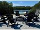 A lovely outdoor firepit is surrounded by black Adirondack chairs on a brick patio, near the water at 7100 Islamorada Cir, Seminole, FL 33777