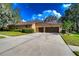 Home exterior featuring a spacious driveway leading to a two-car garage and a well-maintained lawn at 10130 Paddock Oaks Dr, Riverview, FL 33569