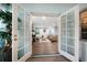 Spacious living room with fireplace viewed through French doors, complemented by wood floors and neutral décor at 1100 S Betty Ln, Clearwater, FL 33756