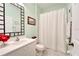 Mint green bathroom with tile floors, shower-tub combination, white vanity and black-framed mirror at 11539 Captiva Kay Dr, Riverview, FL 33569