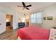Bright bedroom features hardwood floors, a ceiling fan, and white walls and door to ensuite at 11539 Captiva Kay Dr, Riverview, FL 33569