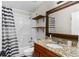 Bright bathroom featuring a shower/tub combo, wooden shelves and a granite countertop vanity with an ornate mirror at 13411 Beechberry Dr, Riverview, FL 33579