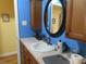 Bathroom sink with ample counter space, cabinet storage, and decorative mirror and blue wall at 15 N Saturn Ave, Clearwater, FL 33755