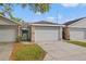 View of the attached one-car garage of home with stone facade accents and concrete driveway at 1763 Castle Rock Rd, Tampa, FL 33612