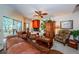 Cozy living room features leather sofa, decorative fireplace, ceiling fan, and a large window overlooking lush greenery at 20 Woodridge Cir, Oldsmar, FL 34677