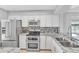 Bright kitchen featuring modern stainless steel appliances, light granite countertops, and white cabinets at 340 Causeway Blvd # 108, Dunedin, FL 34698