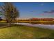 Scenic backyard view with lush green lawn and a tranquil pond reflecting the twilight sky at 4522 Tramanto Ln, Wesley Chapel, FL 33543