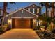 Two-story home showcasing a well-manicured front yard with lush landscaping, palm trees, and a large two-car garage at dusk at 4522 Tramanto Ln, Wesley Chapel, FL 33543