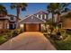 Exterior elevation of a two-story home with a two-car garage, landscaped yard and palm trees at 4522 Tramanto Ln, Wesley Chapel, FL 33543