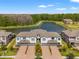 Aerial view of townhouses with a lake and wooded area in the background at 4896 San Martino Dr, Wesley Chapel, FL 33543