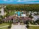 Aerial view of a community pool, clubhouse, and surrounding landscape featuring palm trees and a water slide at 4896 San Martino Dr, Wesley Chapel, FL 33543