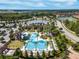 Aerial view of a community pool area showcasing pool design, surrounding landscapes and a nearby lake at 4896 San Martino Dr, Wesley Chapel, FL 33543