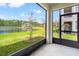 Screened-in patio view overlooking the lush green lawn, tranquil lake, and the building's exterior at 4896 San Martino Dr, Wesley Chapel, FL 33543