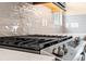 Close-up of a sleek gas stovetop with stainless steel knobs and a stylish tile backsplash at 4896 San Martino Dr, Wesley Chapel, FL 33543