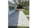 Paver patio and backyard featuring the side of the white home, a tall tree, and green lawn at 525 Crystal Dr, Madeira Beach, FL 33708