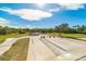 A community skate park featuring concrete ramps and rails, surrounded by lush greenery under a bright blue sky at 5610 Tanagergrove Way, Lithia, FL 33547