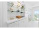 Stylish bar area with glass shelves, decorative accents, and easy access to the balcony at 5850 Gasparilla Rd # M5, Boca Grande, FL 33921