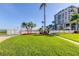 Manicured lawn with palm trees leading to fenced community pool, offering a serene view at 6269 Palma Del Mar S Blvd # 111, St Petersburg, FL 33715