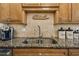 Granite countertop with stainless steel sink and decorative backsplash, complemented by wooden cabinetry and modern appliances at 634 Edgewater Dr # 744, Dunedin, FL 34698