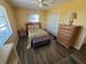 Bright bedroom with wood-look floors features a ceiling fan, closet, and wooden dresser at 823 La Jolla Ave, Sun City Center, FL 33573