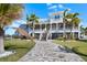 Waterfront home features a columned porch, palm trees, manicured lawn, screened-in lanai, and brick paver walkway at 829 Blue Heron Blvd, Ruskin, FL 33570