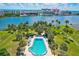 An aerial view shows a sparkling community pool nestled amidst lush landscaping and waterfront views at 10215 Regal Dr # 45, Largo, FL 33774