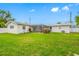 Expansive backyard with lush green grass, screened-in patio, and mature trees under a sunny blue sky at 11601 86Th Ave, Seminole, FL 33772