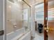 Bathroom with glass enclosed tub, vintage tile walls, black toilet, and neutral tile floor at 11601 86Th Ave, Seminole, FL 33772