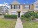 Two-story townhome featuring manicured landscaping, black shutters, tan stucco, and a welcoming walkway to the front door at 1256 Redondo Way, Wesley Chapel, FL 33543