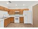 Well-lit kitchen with white appliances, wood cabinets and a stylish backsplash at 1256 Redondo Way, Wesley Chapel, FL 33543