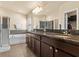 Primary bathroom featuring double vanity with granite counters, soaking tub, and glass enclosed shower at 1426 Main St, Valrico, FL 33594