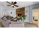 Living room with wood accent wall, gray sectional sofa, ceiling fan, and open access to dining area at 1426 Main St, Valrico, FL 33594