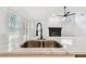 Kitchen island featuring a stainless steel sink with an open view to the light-filled living area and fireplace at 1621 S Keene Rd, Clearwater, FL 33756