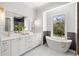Bright bathroom with a soaking tub next to a window and double vanity with marble countertop and gold hardware at 216 N Hesperides St, Tampa, FL 33609