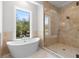 Bathroom featuring a walk-in shower, soaking tub, and large window with natural light at 222 N Hesperides St, Tampa, FL 33609