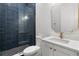 Modern bathroom featuring navy tiled walk-in shower and white vanity with gold hardware at 222 N Hesperides St, Tampa, FL 33609