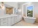 Bright bathroom featuring a soaking tub, walk-in shower, marble floors and a double vanity with gold hardware at 222 N Hesperides St, Tampa, FL 33609