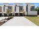 Modern townhomes featuring neutral colors, individual garages, and concrete driveways on a sunny day at 222 N Hesperides St, Tampa, FL 33609