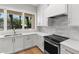Modern kitchen showcasing white cabinetry, stainless steel appliances, and granite countertops beneath a bright window at 222 N Hesperides St, Tampa, FL 33609