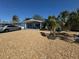 Charming light blue home featuring decorative rock landscaping and mature palm trees at 2344 Tahitian Dr, Holiday, FL 34691