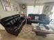 Inviting living room featuring dark leather sofas, neutral walls, and a light patterned rug at 2344 Tahitian Dr, Holiday, FL 34691
